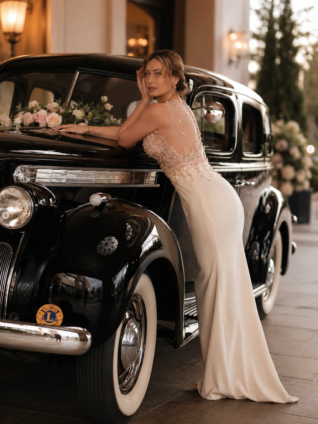 A DORDO client in an ivory evening dress beside a vintage black car