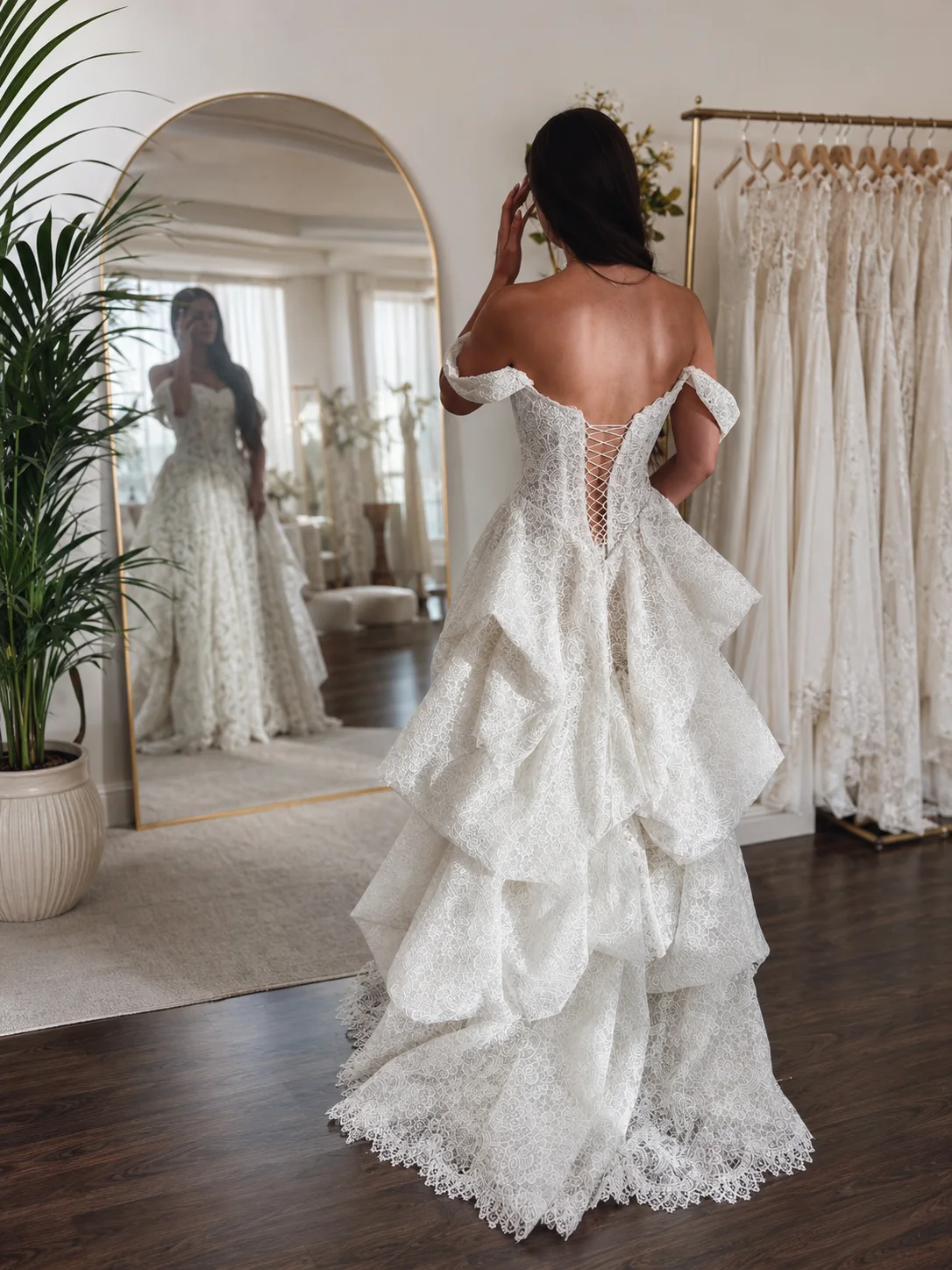 A bride in a sculptural ivory lace gown facing an atelier mirror