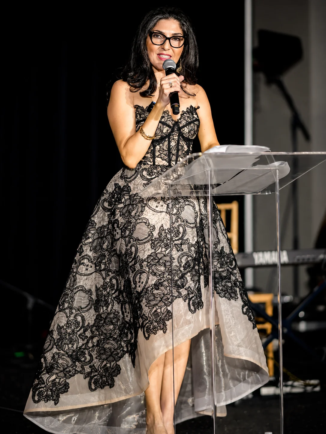 A speaker wearing a black lace DORDO dress